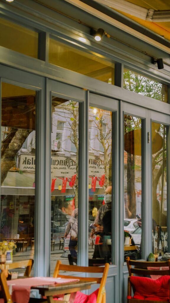 Charming café scene reflecting vibrant street life with glass doors and seating.