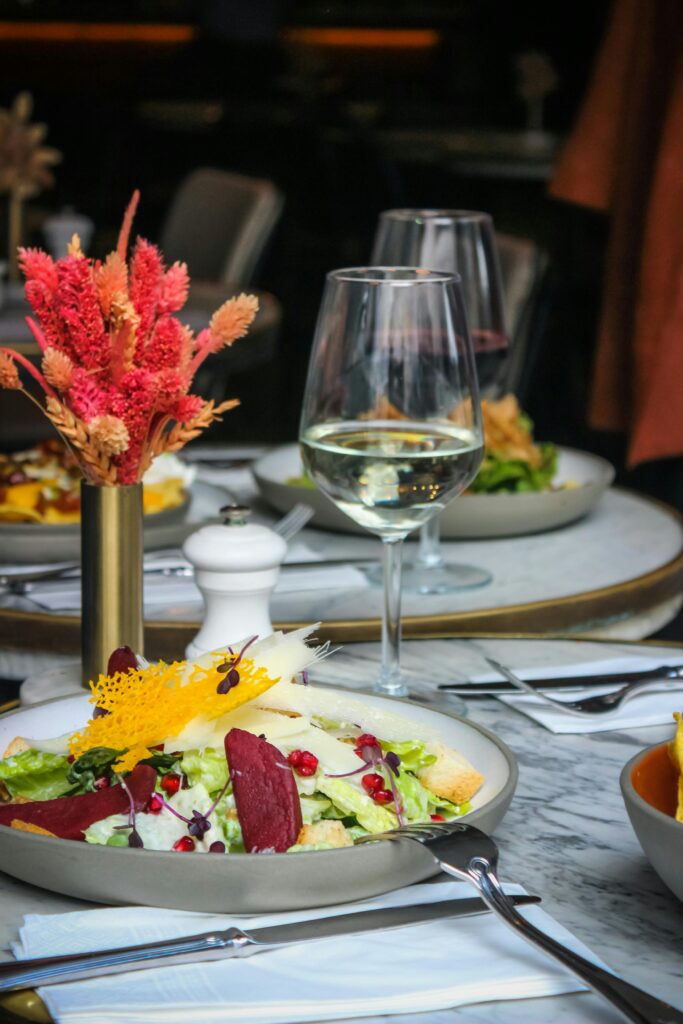 Close-up of a gourmet salad with beetroot and pomegranate, paired with wine on an elegantly set dining table.